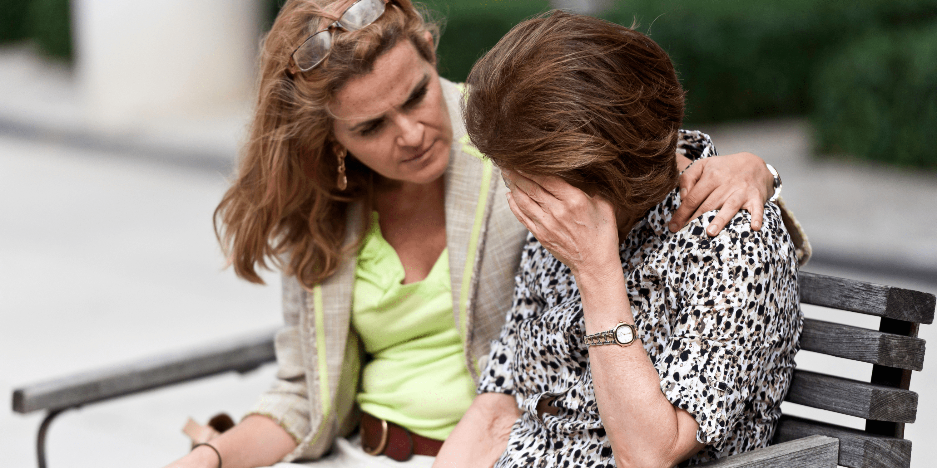 Deux femmes triste ssur un banc. La femme la plus jeune réconforte la plus âgée.