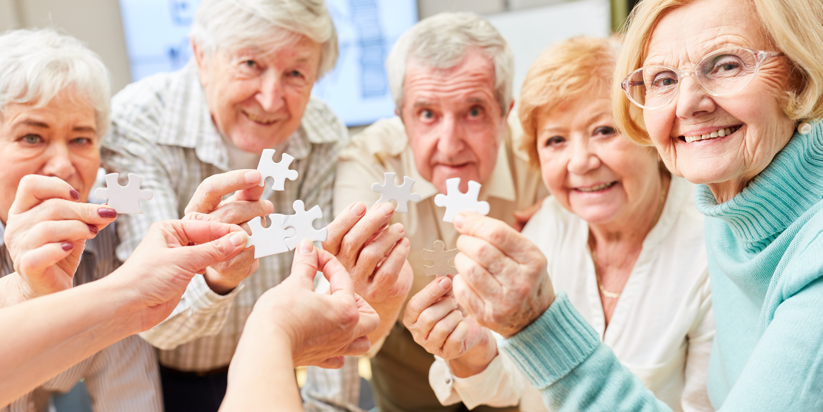 Groupe des personnes âgées qui tiennent des morceaux de puzzle dans leurs mains